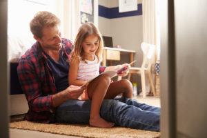 Father and young daughter reading together