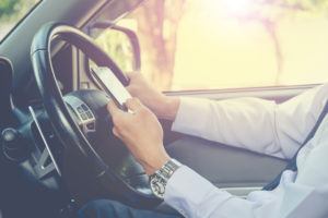Hand using phone sending a text while driving to work