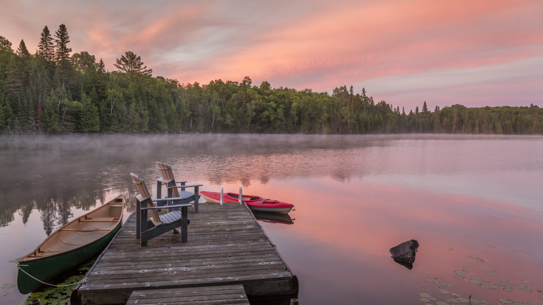 Canoe and kayak moored to a cottage dock at dawn