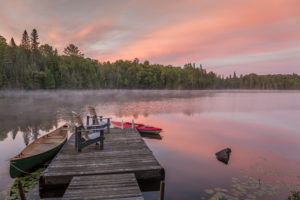 Canoe and kayak moored to a cottage dock at dawn