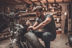 oung man repairing motorcycle in repair shop