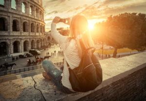Woman tourist selfie with phone camera in hands near the Coliseum in Rome